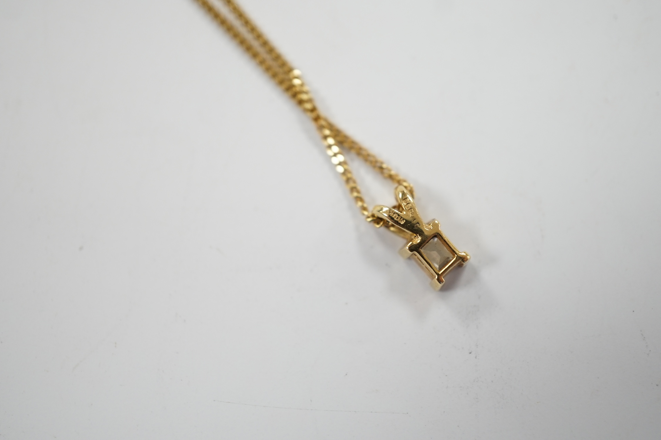 A modern 18ct gold and single stone fancy rectangular cut diamond set pendant, 9mm, on an 18ct gold fine link chain, 46cm, gross weight 3.6 grams.